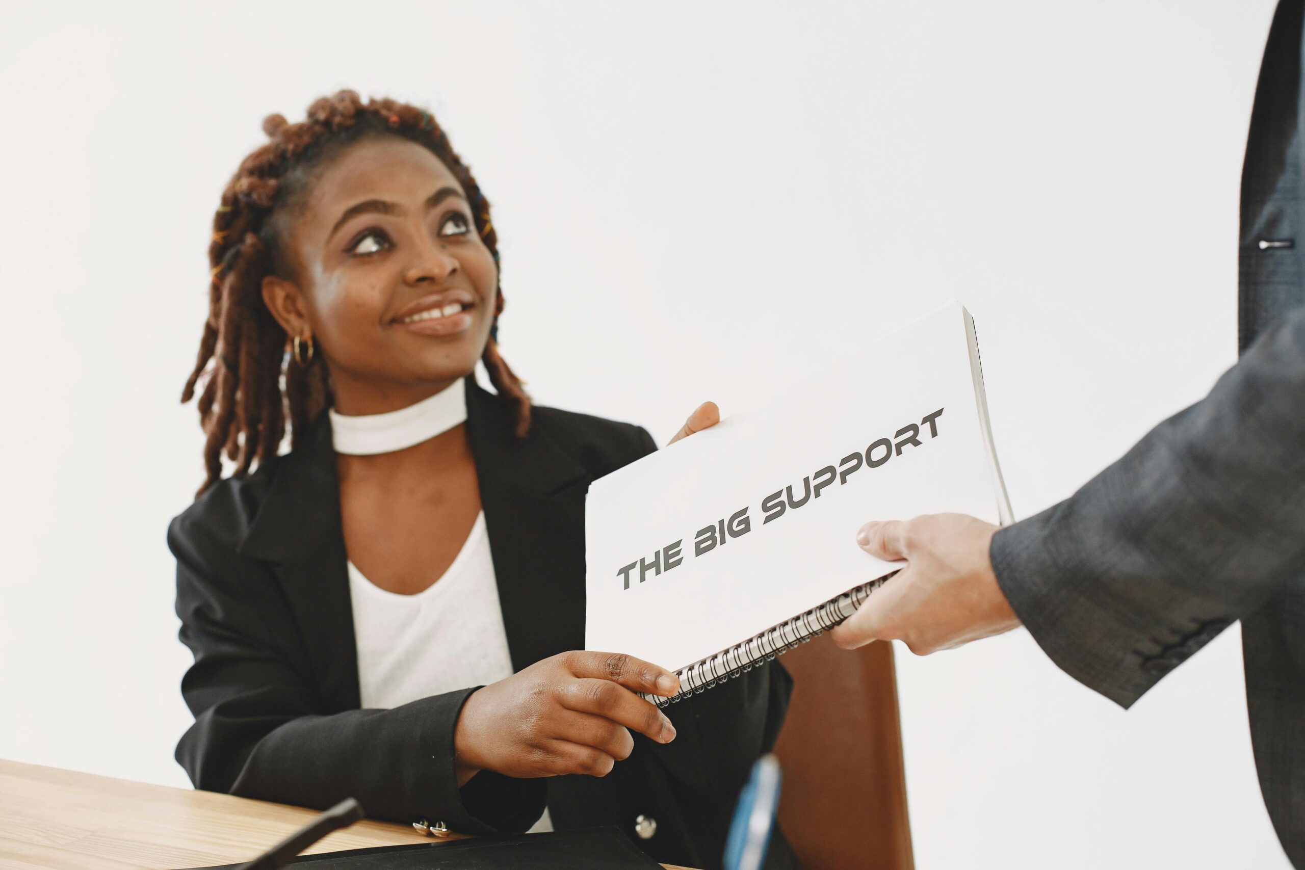 African American woman smiling while receiving a corporate document in a studio setting.
