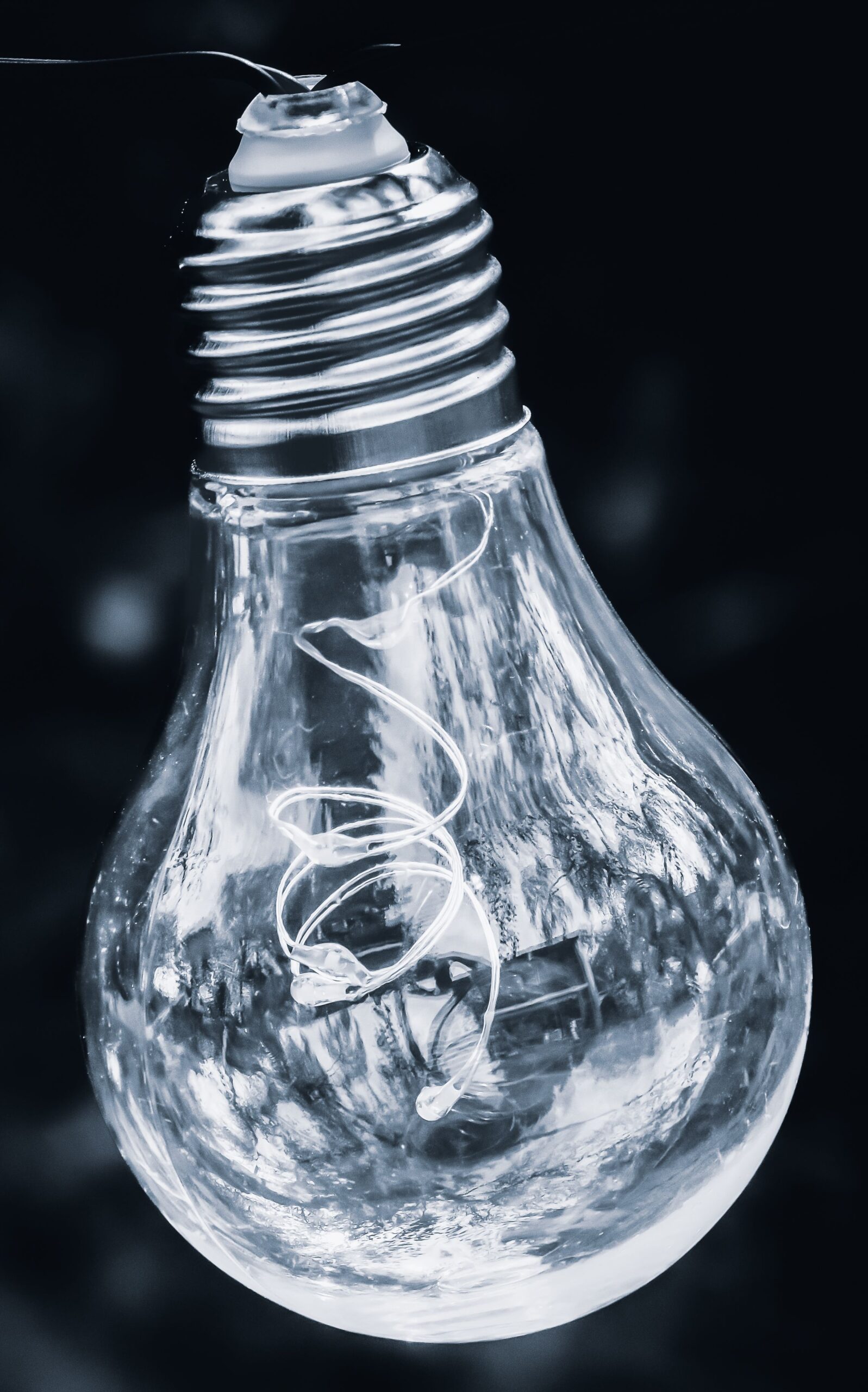 Detailed shot of a hanging light bulb against a dark background, showcasing intricate filament details.